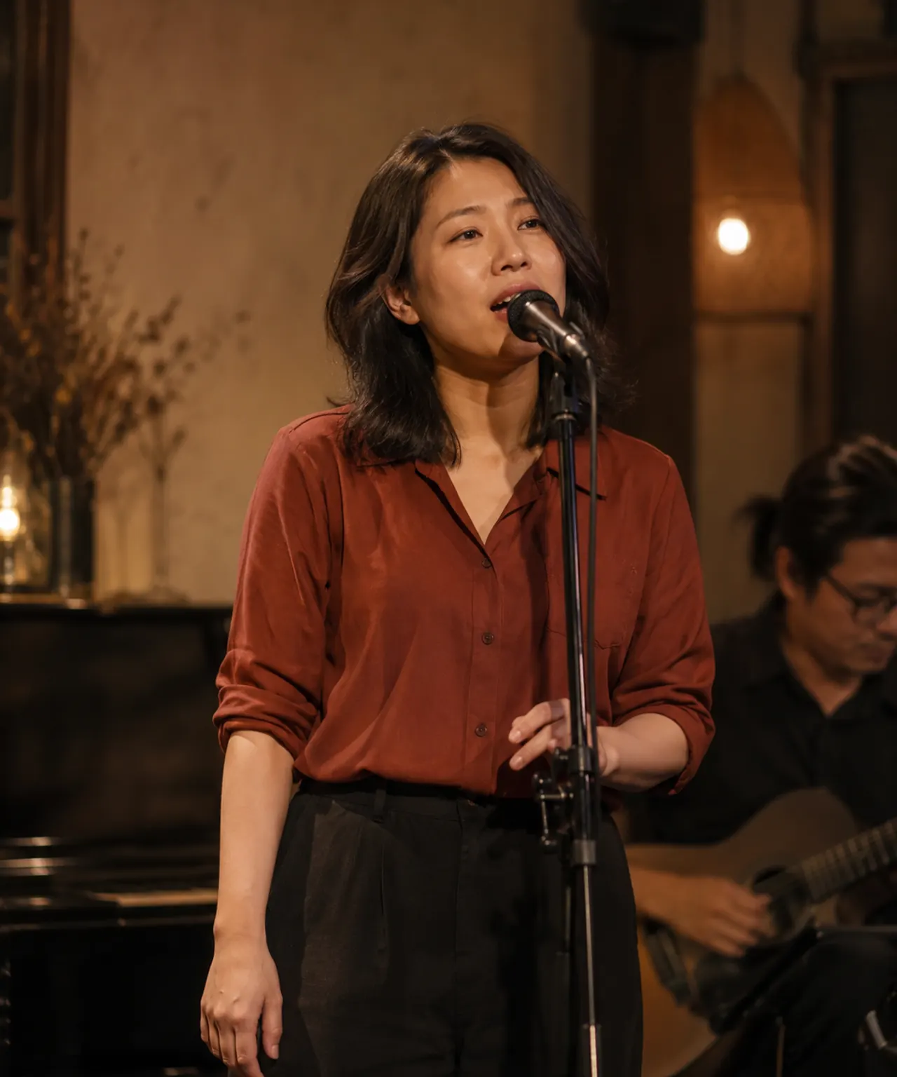 Minh họa bằng AI: nữ ca sĩ Việt Nam biểu diễn với micro trong không gian âm nhạc nhỏ, dưới ánh đèn ấm.